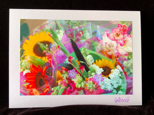 Bouquet of red and yellow sunflowers and pink and white gladiolas at farmer's market stall.