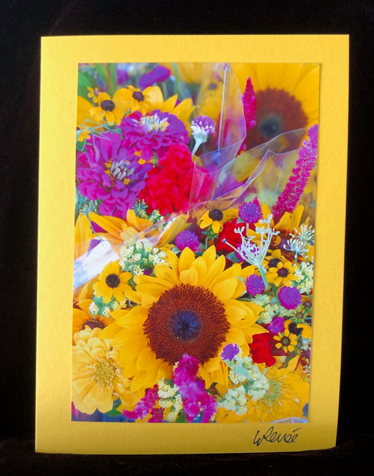 Colorful bouquet of yellow sunflowers, purple clover and purple zinnias at farmers market stall.