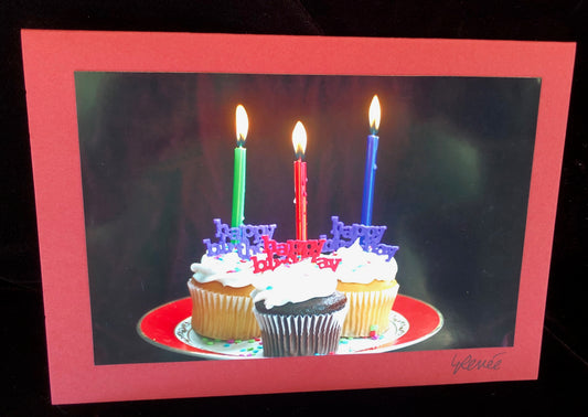 Three cupcakes on plate with Happy Birthday message and lit candles.