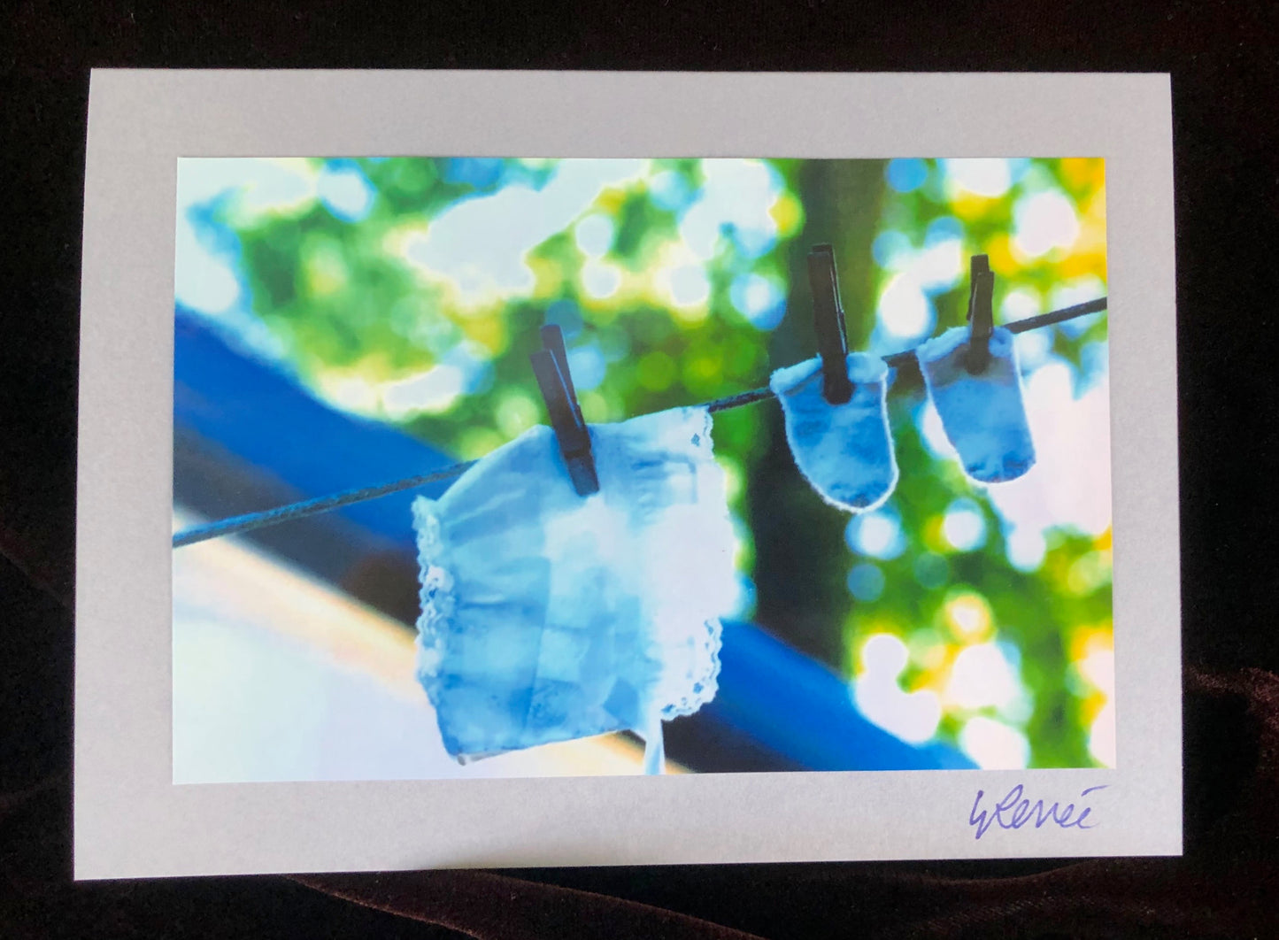 A white baby bonnet and a pair of small socks hanging on a clothesline outside.