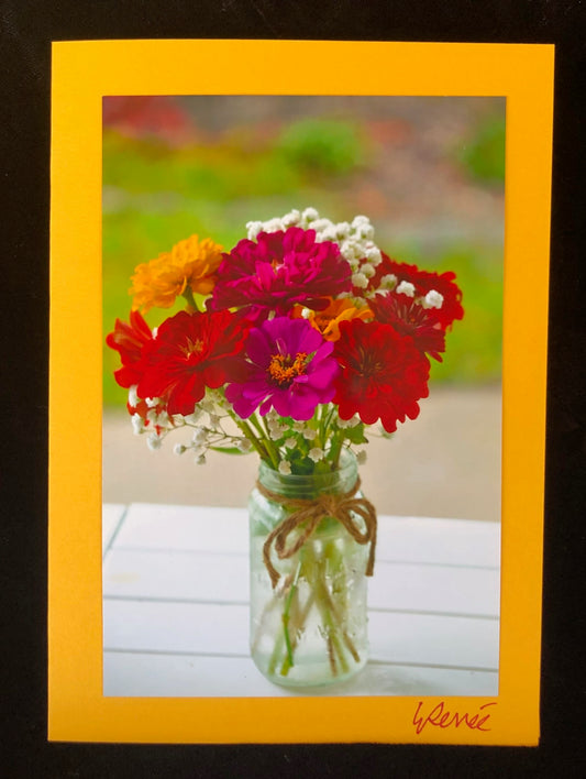 Colorful zinnias and baby's breath in Mason Jar.